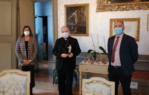 La statuina che raffigura l’imprenditore portata in dono al vescovo di Alba