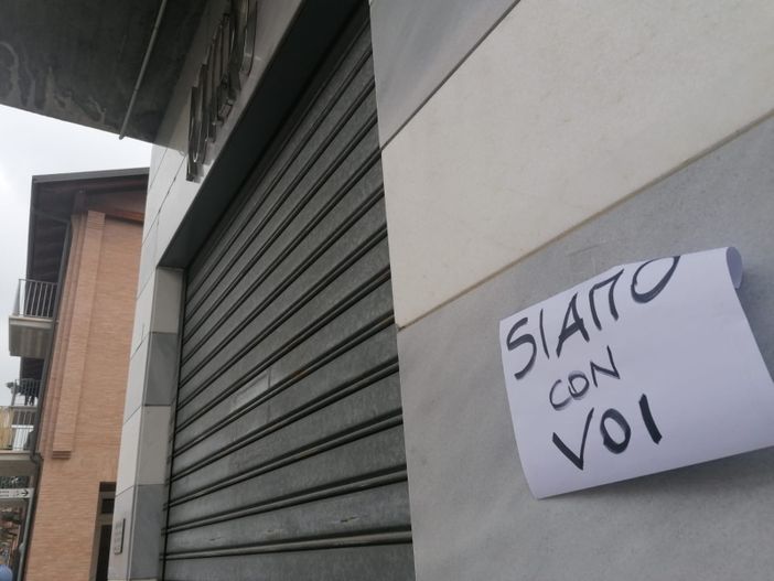 Un cartello di solidarietà appeso di fianco all'ingresso della gioielleria Roggero all'indomani della tragedia