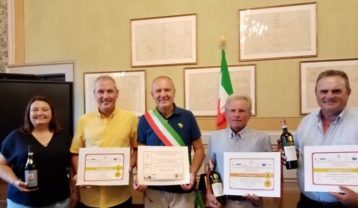 Il sindaco Ezio Cardinale (al centro) con la targa di riconoscimento al Comune di Diano d'Alba, insieme ai titolari delle due aziende premiate